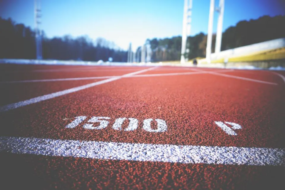 Marca de mil quinientos metros pintada en blanco sobre el pavimento rojo de una pista de atletismo, vista a ras de suelo